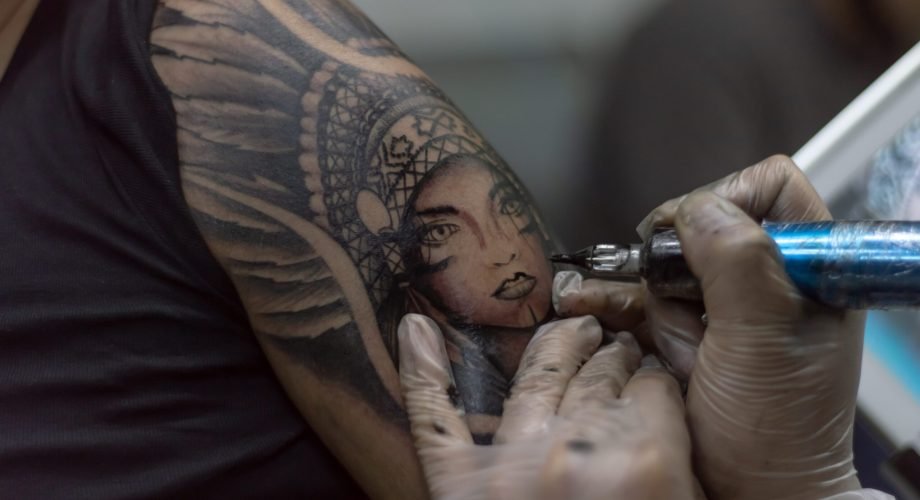 Closeup shot tattoo artist holding a tattoo machine tattooing a person A closeup shot tattoo artist holding a tattoo machine tattooing a person