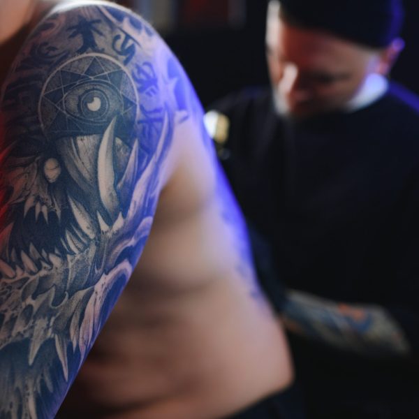 Tattooing. Man creating a picture on his back by a professional tattoo artist.