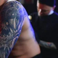 Tattooing. Man creating a picture on his back by a professional tattoo artist.